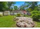 Lush backyard featuring a fire pit, stone patio, green lawn, and mature trees at 672 W Oak Forest Dr, Charleston, SC 29407
