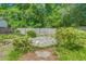 Landscaped backyard featuring a stone patio surrounded by lush greenery and a wood fence at 672 W Oak Forest Dr, Charleston, SC 29407