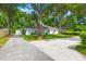 Exterior view of the single Gathering home featuring a long driveway, mature trees, and lush landscaping at 672 W Oak Forest Dr, Charleston, SC 29407