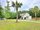 Inviting two-story home featuring a gravel driveway, lush lawn, and mature palm trees at 9489 Sidneys Rd, Round O, SC 29474