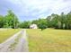 Spacious lot with gravel driveway, lush lawn, and mature trees at 9489 Sidneys Rd, Round O, SC 29474