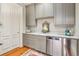 Elegant wet bar with gray cabinets, granite countertop, stainless steel dishwasher, and hardwood floors at N Blvd, Mount Pleasant, SC 29464