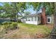 View of home's backyard featuring lawn, mature trees, brick chimney, and sunroom at 109 New Spring Ct, Summerville, SC 29485