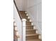 Elegant staircase with carpeted steps, wood banister, and detailed white wainscoting for a classic look at 1153 King St, Charleston, SC 29403