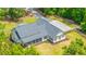 Aerial view of a well-maintained white home with a screened porch and a large gravel driveway surrounded by lush greenery at 1375 Tannanger Trl, Awendaw, SC 29429