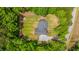 An aerial view displays a well-maintained backyard with a firepit, surrounded by a fence and an abundance of vibrant green trees at 1375 Tannanger Trl, Awendaw, SC 29429