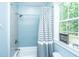 A cozy bathroom with blue accent wall tile, shower-tub combo, and a window for natural light at 1375 Tannanger Trl, Awendaw, SC 29429