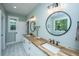 Bright bathroom with double sinks, wooden countertop, patterned tile floor, and circular mirrors at 1375 Tannanger Trl, Awendaw, SC 29429