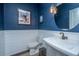Modern powder room with white wainscoting, blue walls, a unique vanity, and stylish decor at 1375 Tannanger Trl, Awendaw, SC 29429