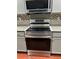 Close-up of stainless steel range with gray cabinets, modern backsplash, and granite countertops in the updated kitchen at 1401 Dabbling Duck Dr, Summerville, SC 29483