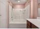 Close up of bathtub with white tiled wall surround, rainfall shower head and a dark wood vanity nearby at 1533 Bluewater Way, Charleston, SC 29414