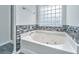 A jetted bathtub is framed by decorative tile and features a textured glass window at 1582 Ocean Neighbors Blvd, Charleston, SC 29412