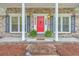 Close-up of inviting front porch with bright red door, plants, and a 