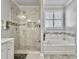 Bright bathroom featuring glass shower, soaking tub, and large window with white shutters at 209 Celestial Blvd, Summerville, SC 29486