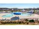 Community pool with lake view, beach umbrellas, lounge chairs and splash pad zones, with nearby neighborhood in background at 209 Celestial Blvd, Summerville, SC 29486