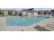 Outdoor community pool area with lounge chairs, sun umbrellas, pool users, and residential homes at 302 Elm Hall Cir, Summerville, SC 29483