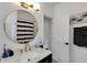Modern bathroom featuring a marble countertop vanity, round mirror, and a black and white striped shower curtain at 3113 Edenvale Rd, Johns Island, SC 29455