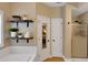 Well lit bathroom featuring a tub, tiled walls, floating shelves and a glass shower door at 3113 Edenvale Rd, Johns Island, SC 29455