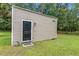 Exterior shot of an outbuilding with horizontal siding, a black door, and green lawn at 3113 Edenvale Rd, Johns Island, SC 29455