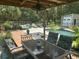 Cozy covered outdoor patio with a dining table and lounge area overlooking a pool and well-maintained garden at 3113 Edenvale Rd, Johns Island, SC 29455