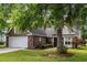 Charming brick home featuring manicured lawn, mature trees, and a two-car garage at 420 Manorwood Ln, Charleston, SC 29414