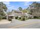 Charming two-story home with a balcony, mature trees, lush landscaping, and paved driveway at 718 Parish Rd, Charleston, SC 29407
