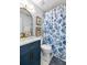 Charming bathroom featuring marble countertop, gold fixtures, blue vanity, and a decorative shower curtain at 638 Stono Edge Dr, Charleston, SC 29412
