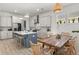 Bright kitchen features white cabinets, stainless steel appliances, island with bar stools, and a wooden dining table at 716 Triangle Ln, Summerville, SC 29486