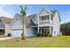 Inviting two-story home featuring a quaint porch balcony and a manicured lawn with a young palm tree at 8402 Loggers Run, North Charleston, SC 29420