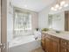 Bathroom features a soaking tub, window with greenery, and wood cabinets at 9019 Parlor Dr, Ladson, SC 29456