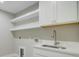Functional laundry room featuring a sink, quartz countertops, floating shelves, and white cabinets at 924 Trent St, Charleston, SC 29414