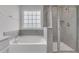 Bright bathroom with tub, tiled shower, chrome hardware, and a frosted window at 9998 Winged Elm St, Ladson, SC 29456