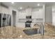 Close-up of a sink and granite-topped island with stainless steel appliances and white cabinets in background at 9998 Winged Elm St, Ladson, SC 29456