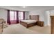 Bright main bedroom featuring a wooden bed set, large windows with curtains, and neutral carpeting at 9998 Winged Elm St, Ladson, SC 29456