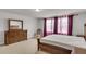 Spacious main bedroom features a wood dresser, wooden bed set, large windows with curtains, and neutral carpeting at 9998 Winged Elm St, Ladson, SC 29456