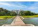 Straight wooden dock leading to marshy grassland with a large building beyond at 108 Fairbanks Oak Aly # 201, Charleston, SC 29492