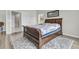 Bedroom with stylish wood frame bed with decorative blue and white quilt and marble bathroom in open doorway at 1273 Locals St, Summerville, SC 29485