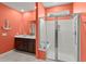 Bathroom featuring dual sinks, dark wood cabinets, glass-enclosed shower, and bright coral-colored walls at 130 Stagecoach Ave, Summerville, SC 29486