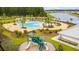Aerial view of a large community pool, playground, and lakefront with palm trees and seating areas at 130 Stagecoach Ave, Summerville, SC 29486