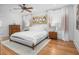 Bright main bedroom featuring hardwood floors, shutters, ceiling fan, and large bed with decorative oyster art at 1543 Wando Landing St, Charleston, SC 29492
