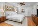 Bright main bedroom with wood floors, ceiling fan, and large bed with decorative oyster art above at 1543 Wando Landing St, Charleston, SC 29492