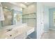 Light blue bathroom featuring a walk-in shower, large mirror, glass shelving, and vanity sink at 174 Revetment Ln, Mount Pleasant, SC 29464