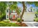 Charming two-story home featuring a brick facade, siding, a welcoming orange front door, and lush landscaping at 174 Revetment Ln, Mount Pleasant, SC 29464