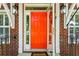 Close-up of the vibrant orange front door framed by stylish exterior sconces and brick detailing at 174 Revetment Ln, Mount Pleasant, SC 29464