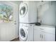 Efficient laundry room features stacked washer and dryer, storage cabinets, and exterior door at 2177 Gulf Dr, Mount Pleasant, SC 29464