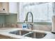 Close-up view of stainless steel kitchen sink featuring patterned window sheers and marble countertops at 2177 Gulf Dr, Mount Pleasant, SC 29464