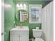 Clean bathroom with bright green walls, new white vanity, round mirror, and natural light from the window at 264 Columbia Dr, Ladson, SC 29456