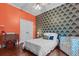 The bedroom is brightly decorated with orange walls, patterned wall paper, white bedding and hardwood floors at 2792 River Vista Way, Mount Pleasant, SC 29466