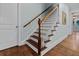 Staircase with wood treads and a white spindle railing leading to a naturally lit entryway at 2792 River Vista Way, Mount Pleasant, SC 29466