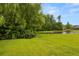 Lush backyard with expansive green lawn leading to a serene pond surrounded by mature trees at 2881 Rutherford Way, Charleston, SC 29414